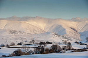 Pasture Prints: View of snow covered farmland and fells in evening sunlight