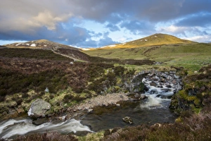 View of stone bridge over river in glen, in evening sunlight, Clunie Water, near Braemar, Cairngorms N. P