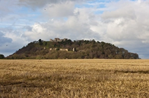 View over stubble field towards castle on sandstone crag, Beeston Castle, Beeston, Cheshire, England, january