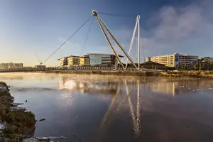 View of tidal river with footbridge and university building at sunrise, Newport City Footbridge, River Usk, Newport