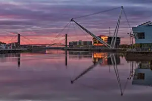 View of tidal river with footbridge and university building at sunrise, Newport City Footbridge, River Usk, Newport