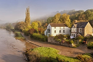Gloucestershire Prints: View of village on riverbank in mist at dawn