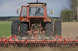 Volvo tractor pulling harrows, cultivating arable field, Sweden