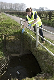 Water quality scientist from Thames Water, taking samples to be tested for traces of metaldehyde, carbetamide and propyzamide, Wormleigton Stream, near Claydon, Oxfordshire, England, march