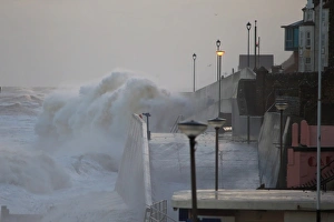 Flood Prints: Waves crashing against seawall of seaside town during tidal surge
