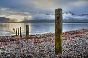 Wooden posts on shore of sea loch at sunset, Loch Linnhe, Onich, Highlands, Scotland, april