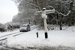 Cars Prints: Wooden signpost and car in snow covered lane