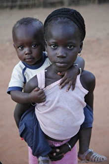 Local Prints: Young girl carrying younger brother on back, Gambia, january